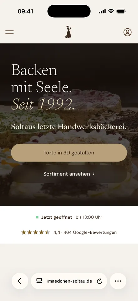 Die Startseite des Schokoladenmädchens am iPhone: „Backen mit Seele. Seit 1992.“, die Knöpfe „Torte in 3D gestalten“ und „Sortiment ansehen“, darunter die Öffnungszeit und 4,4 Sterne aus 464 Google-Bewertungen.
